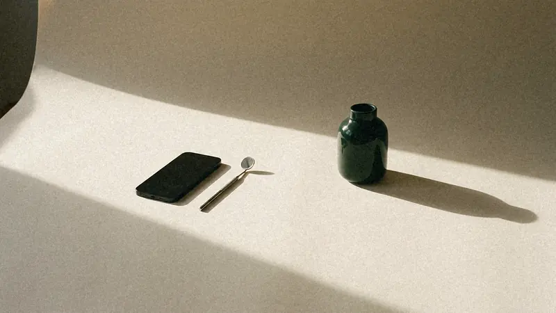 Ekranı aşağı bakan bir akıllı telefon ve yanında küçük bir diş hekimi aynası